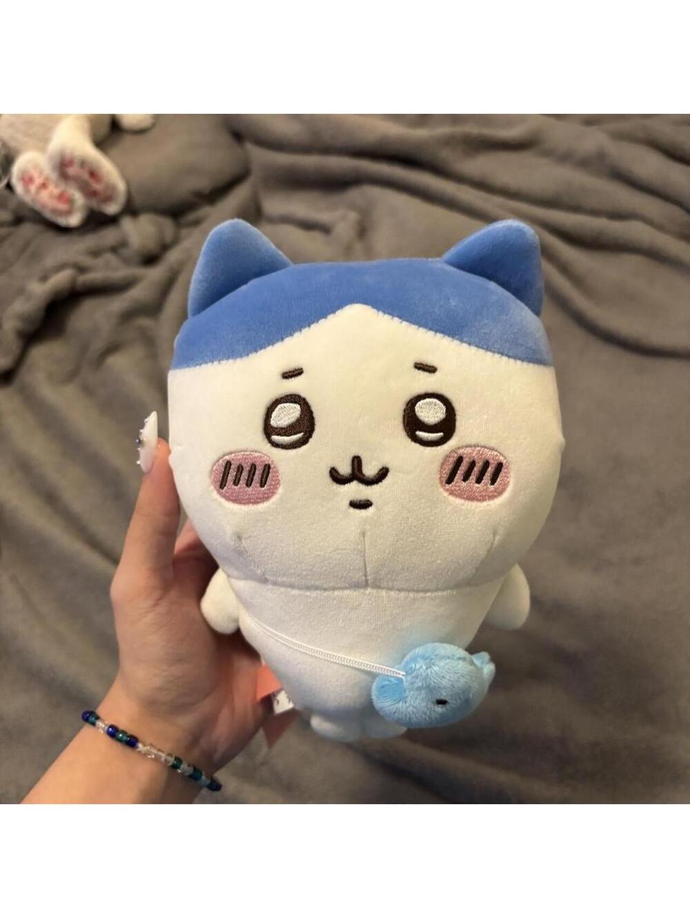 Chiikawa plushie with blue ears and tail, white body, pink cheeks and black eyes